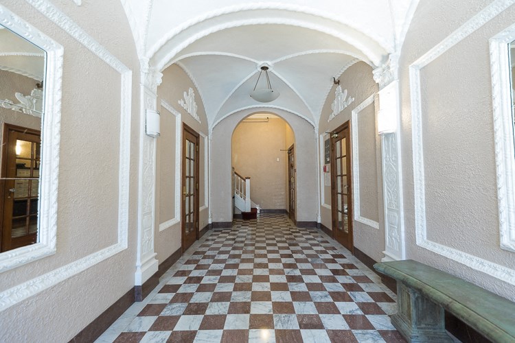 a hallway with a checkered floor and a bench