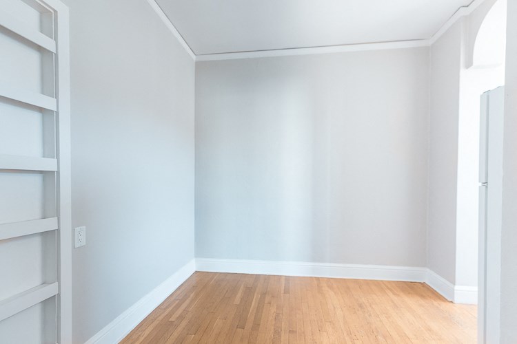an empty room with white walls and a wooden floor