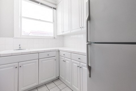 a white kitchen with white cabinets and a refrigerator