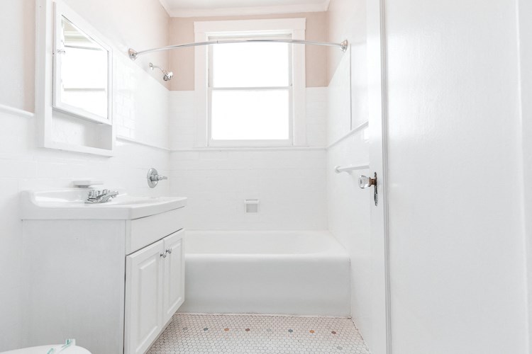 a white bathroom with a window and a sink and a shower