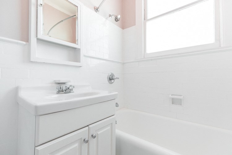 a white bathroom with a sink and a bath tub