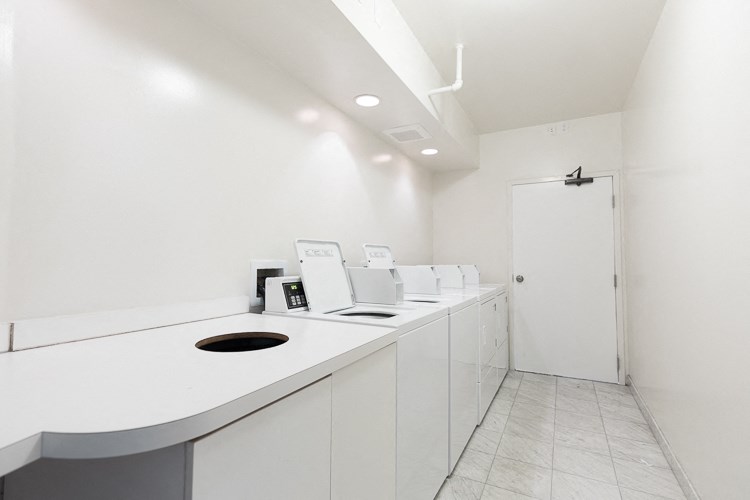 a laundry room with white counters and a white door
