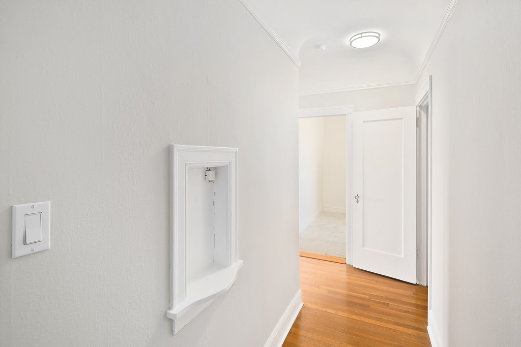 a living room with white walls and a door to a hallway
