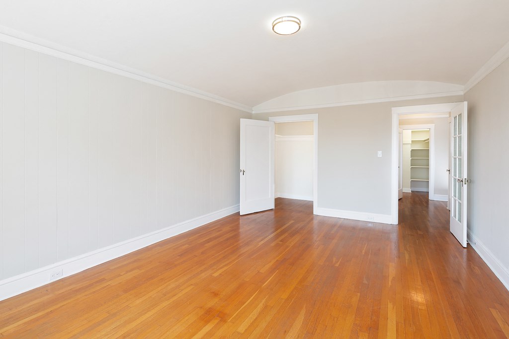 an empty living room with wood floors and white walls