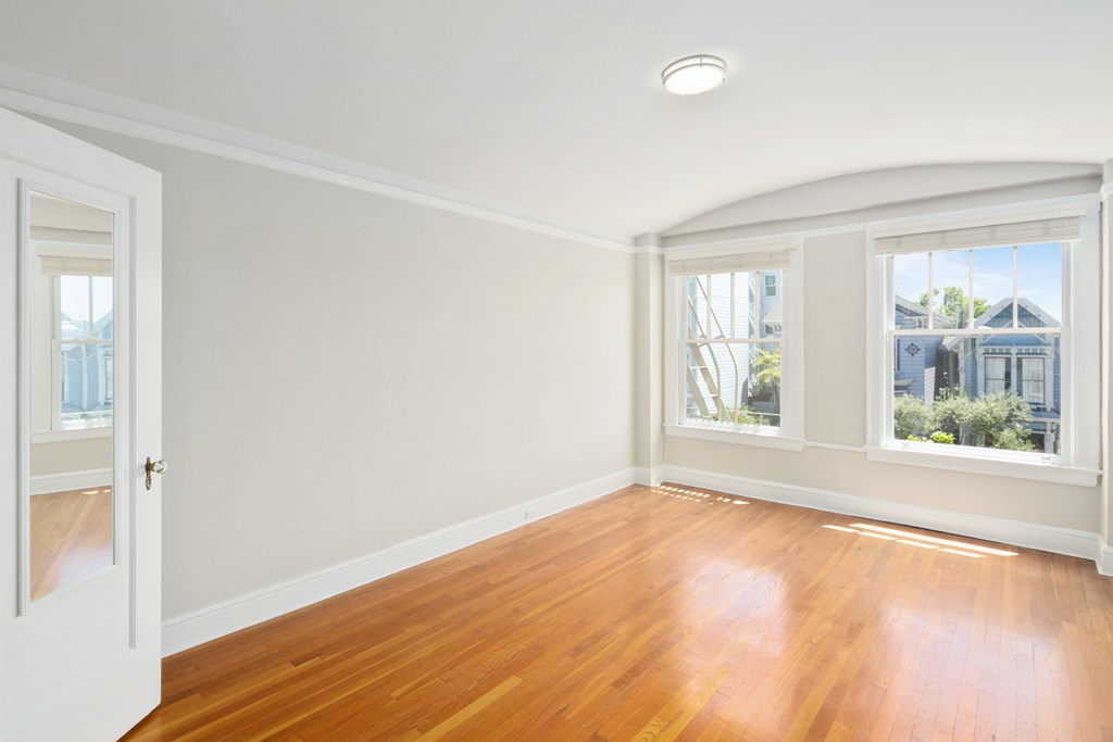 an empty living room with wood floors and white walls