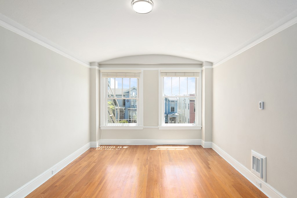 an empty living room with three windows and a wooden floor