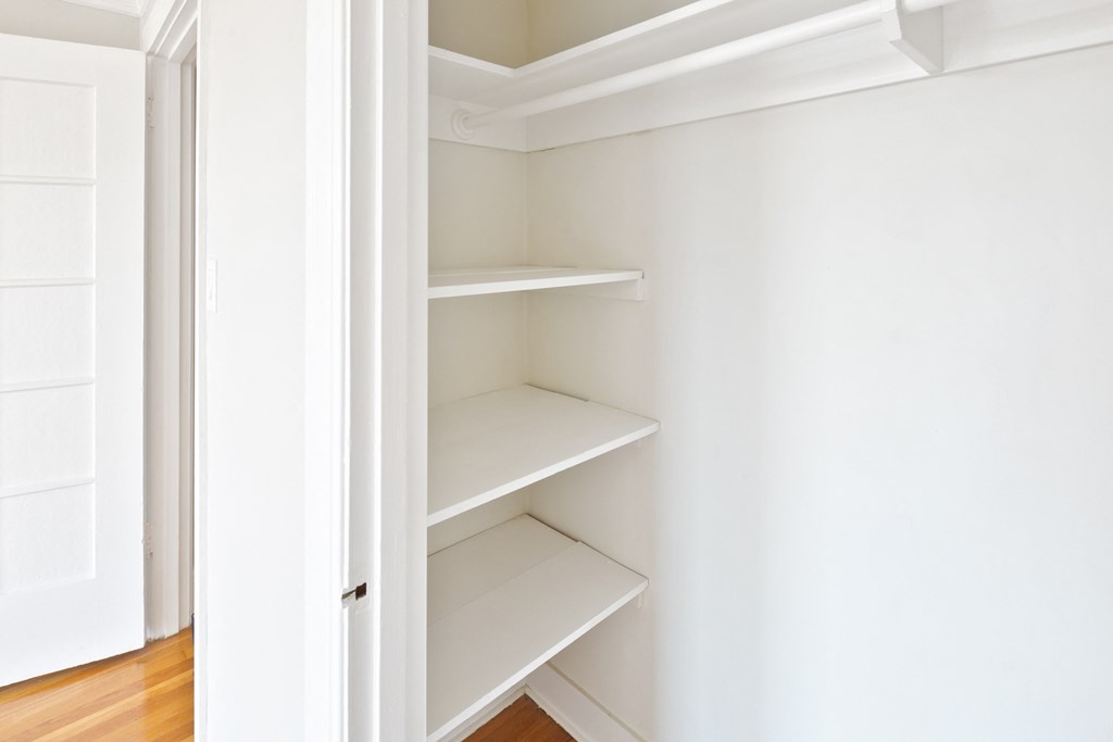 a walk in closet with white shelves and a door