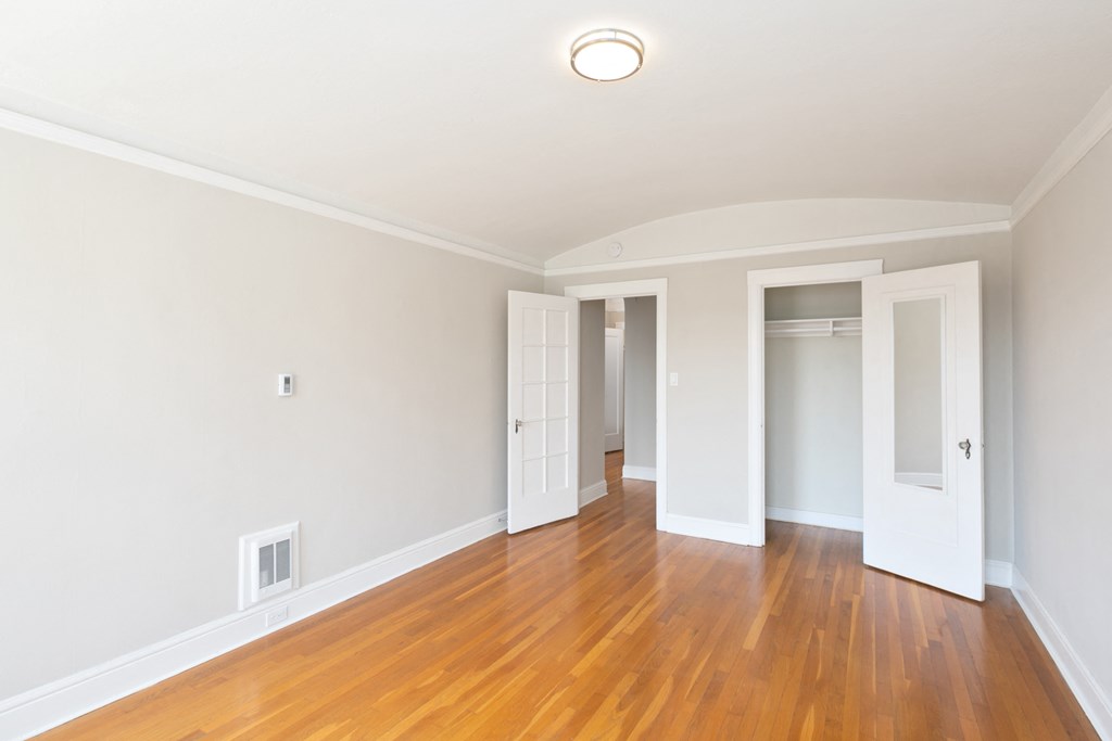 an empty living room with wood floors and white walls