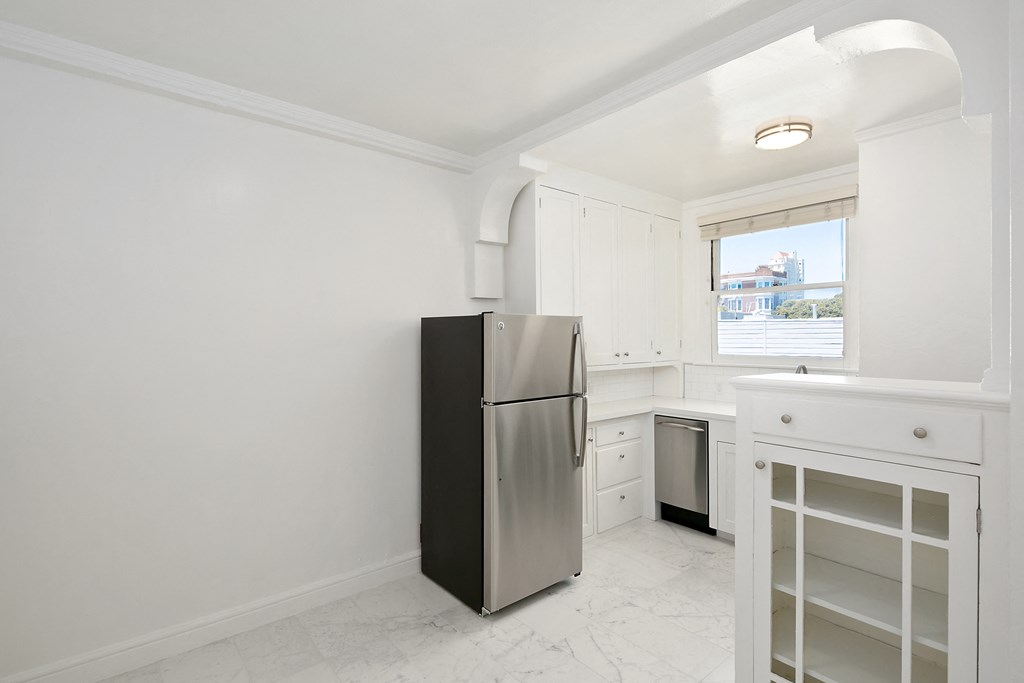 a white kitchen with a refrigerator and a window