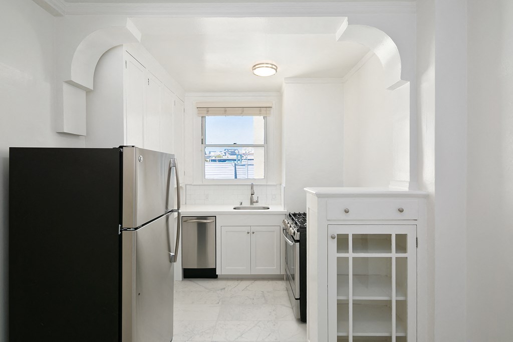 a kitchen with white cabinets and a black refrigerator