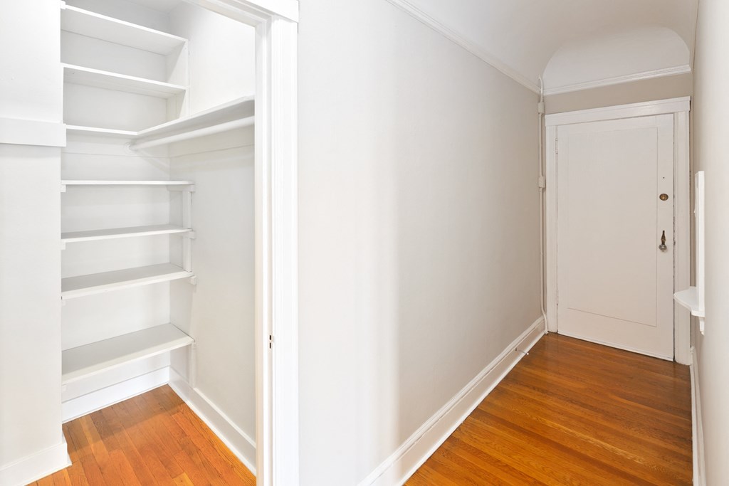 a room with white shelves and a door and a wood floor