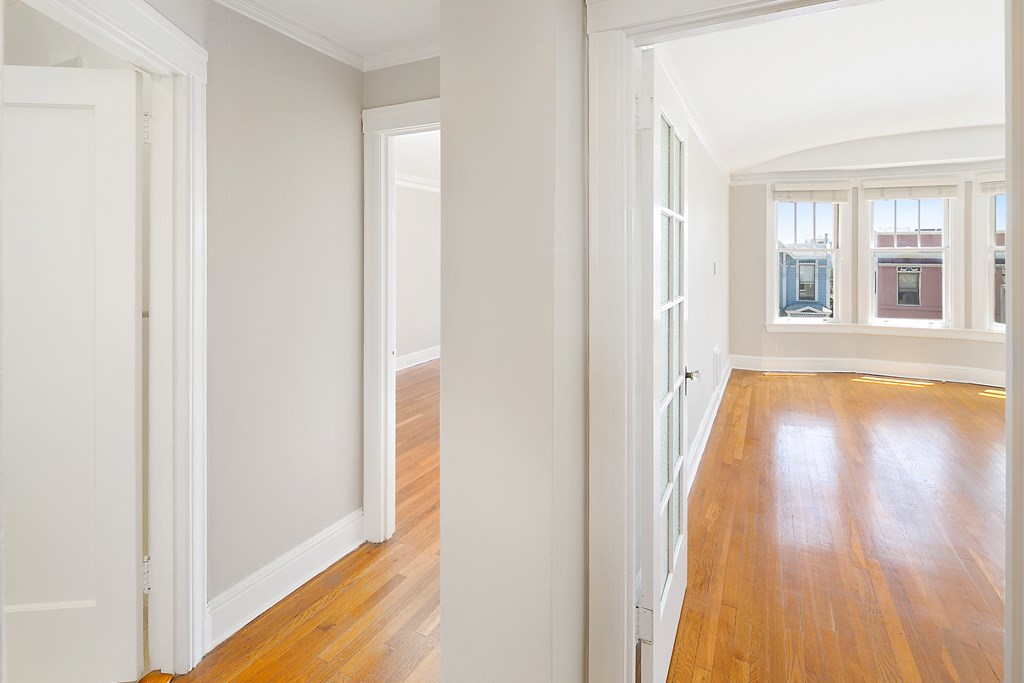 a living room and a hallway with wood floors and white walls