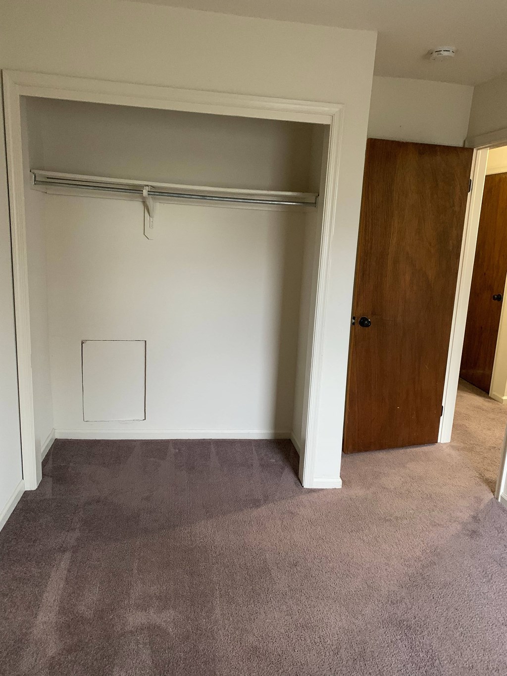 a bedroom with a closet and a carpeted floor