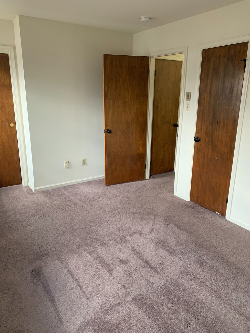an empty room with three doors and carpeting