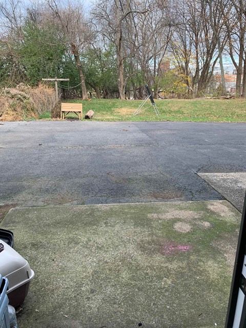 an empty parking lot with a bench in the grass