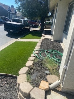 a side yard with a green hose in front of a house