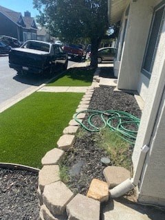 a side yard with a green hose in front of a house