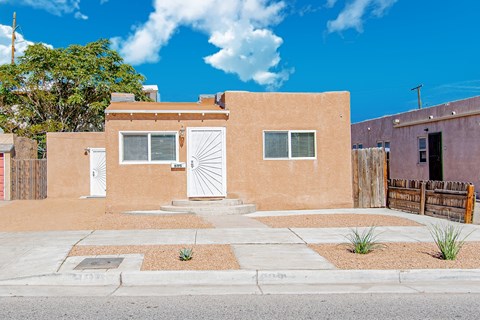 a small brick house with a white door and a sidewalk