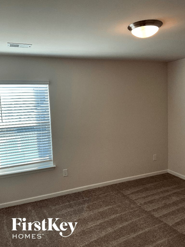 an empty living room with a window and a carpet