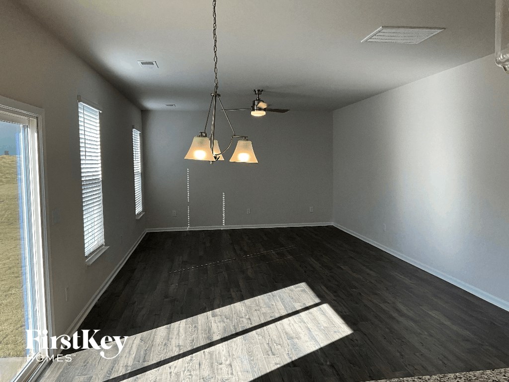 an empty living room with wood floors and a chandelier