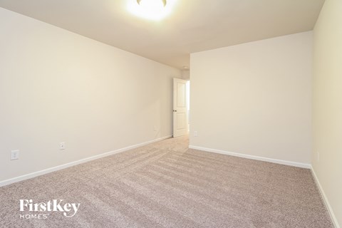 a spacious living room with carpet and white walls