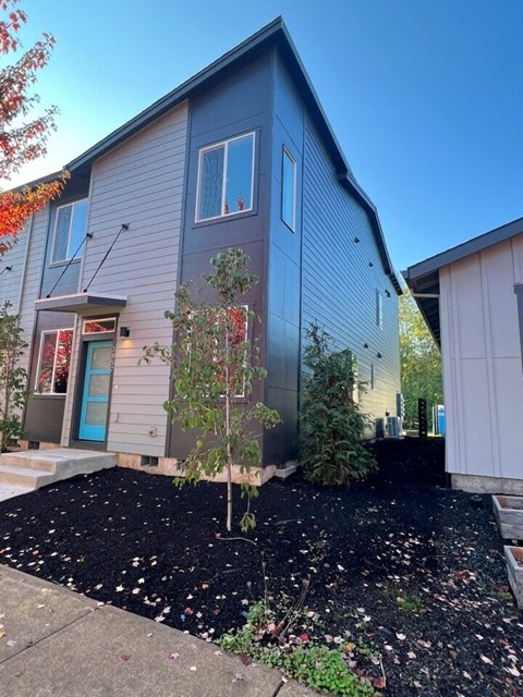 the front of a house with a yard and a tree