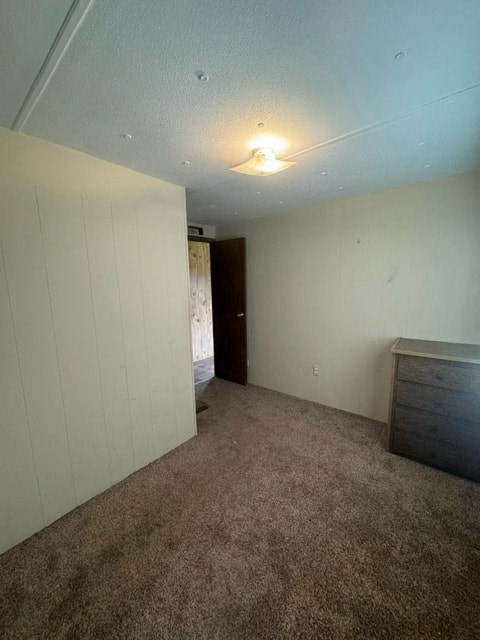 A room with a carpeted floor and a door in the background.