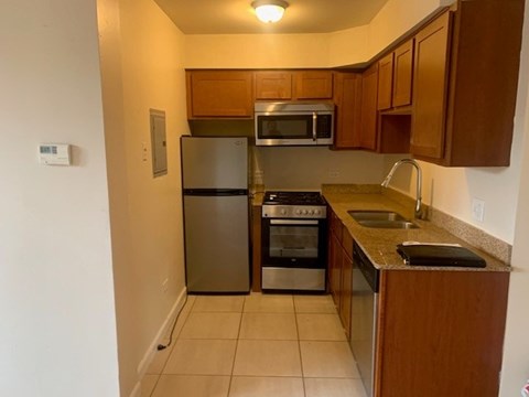 A kitchen with a refrigerator, oven, microwave, and sink.