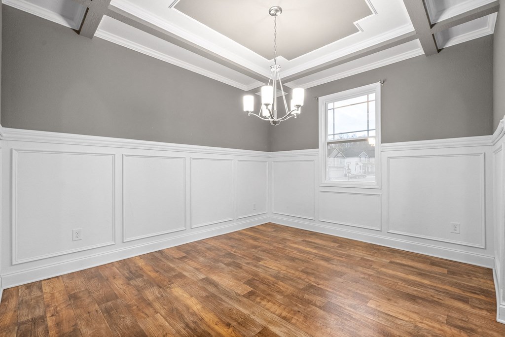 the living room of a house with gray walls and a wooden floor and a window