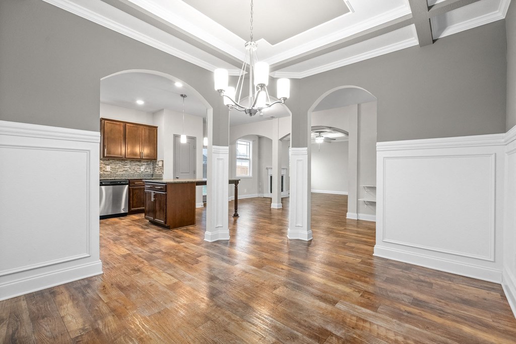 a kitchen and living room with white walls and wood floors