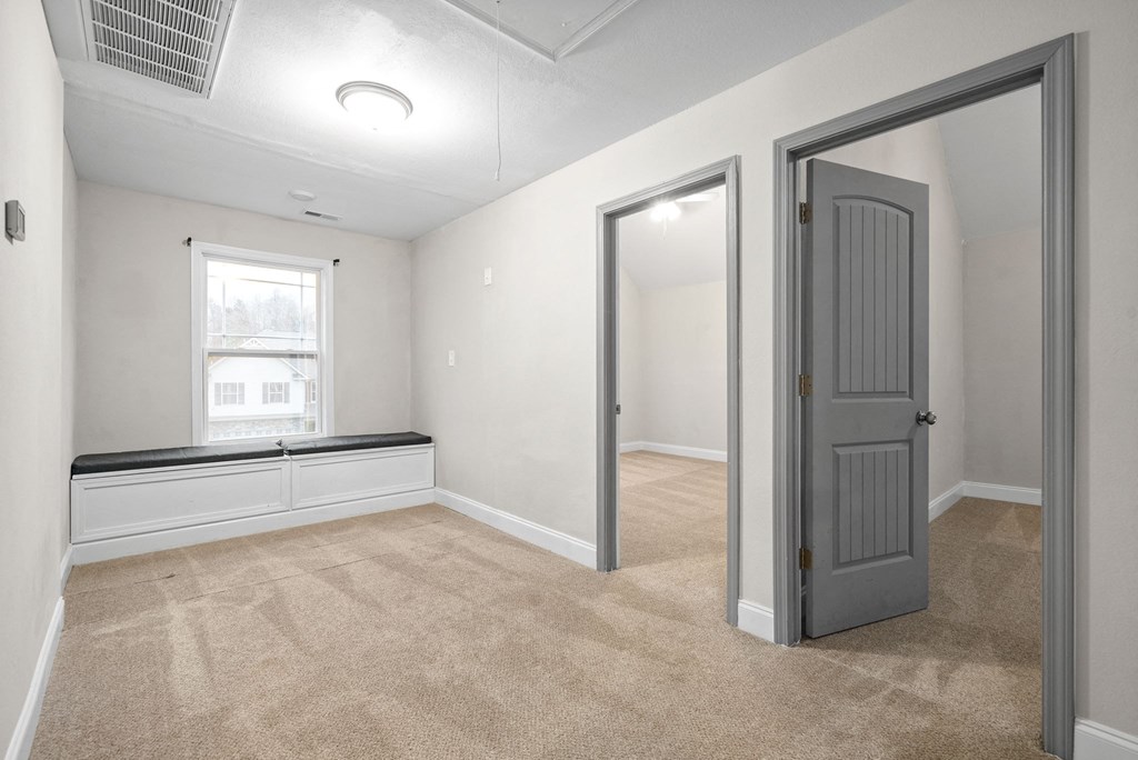 an empty living room with a gray door and a window