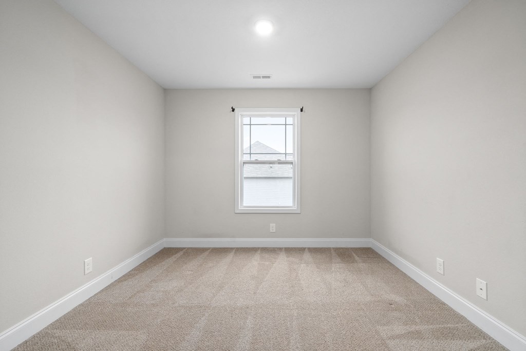 an empty room with a window and white walls