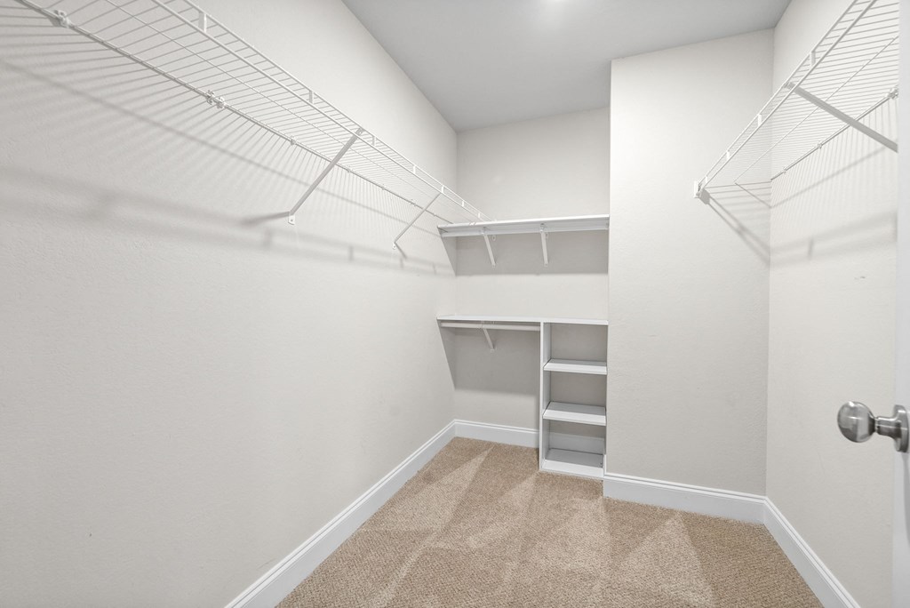 a walk in closet with shelves and a mirrored closet door