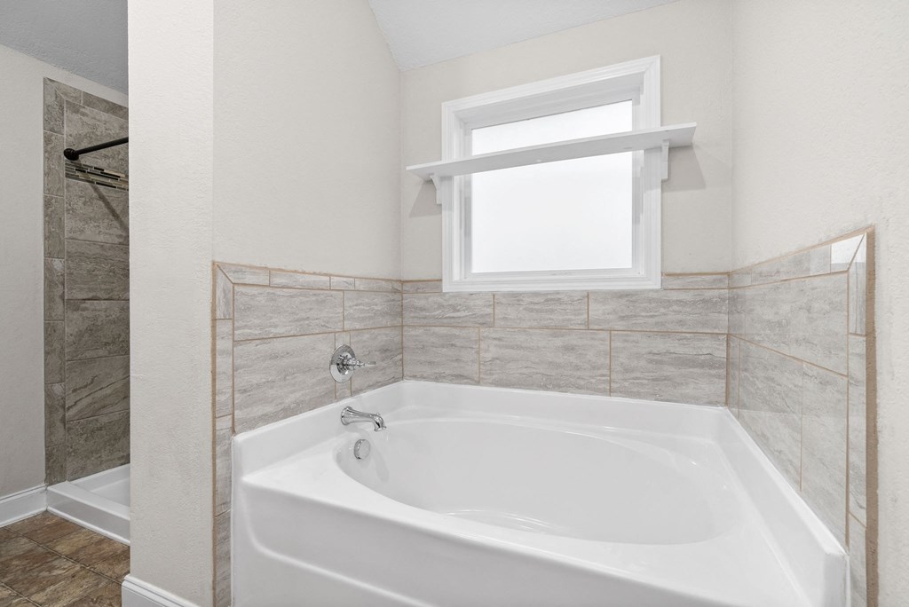 a bathroom with a large white tub and a window