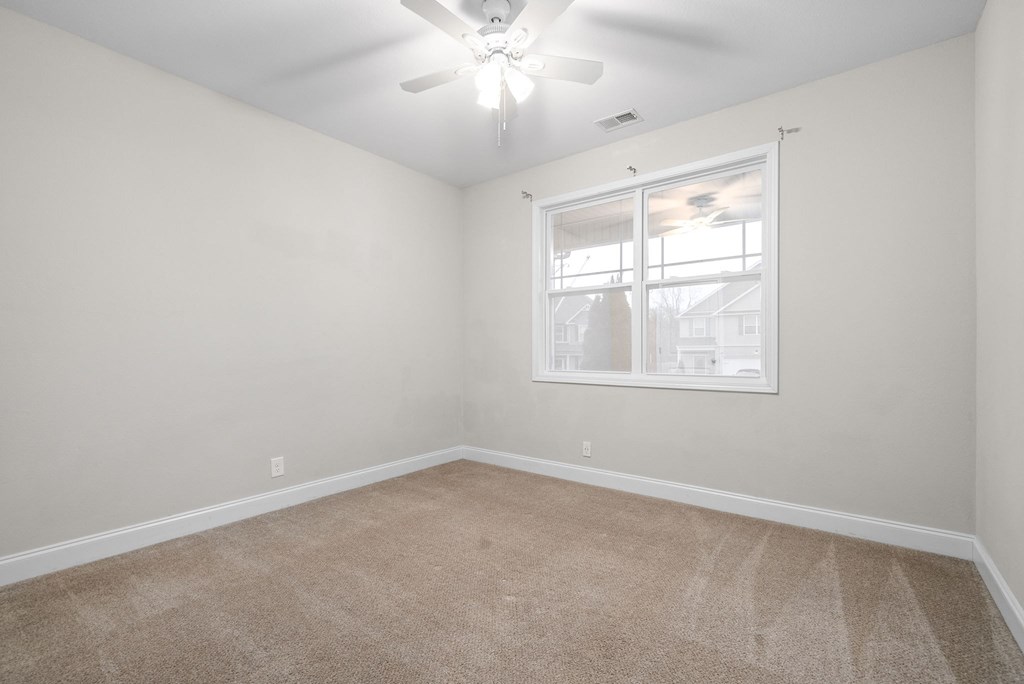 an empty room with a window and a ceiling fan