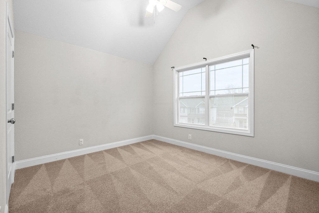 an empty bedroom with a window and carpeting
