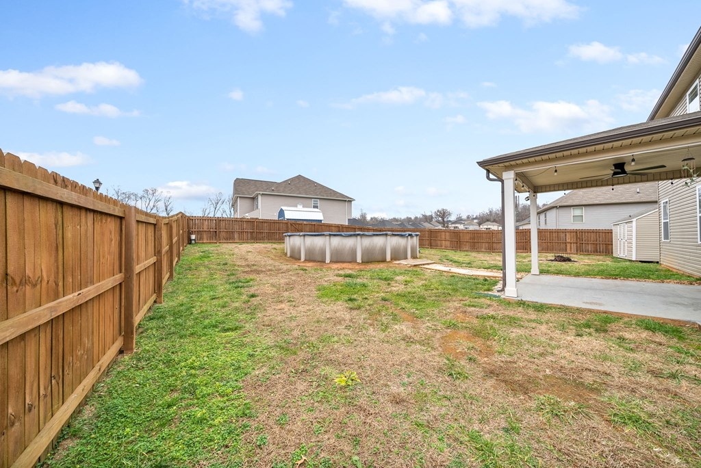 the back yard of a house with a wooden fence and a yard with a barrel