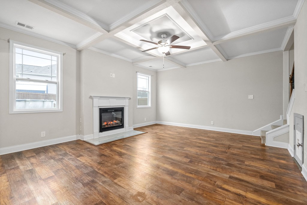 an empty living room with a fireplace and a ceiling fan