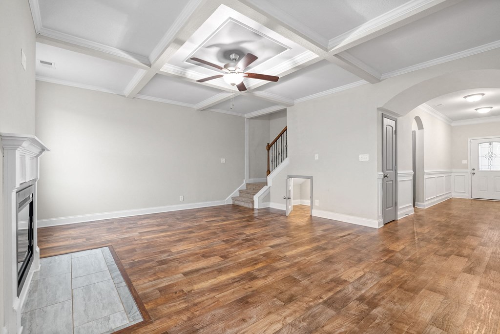 an empty living room with a ceiling fan and a staircase