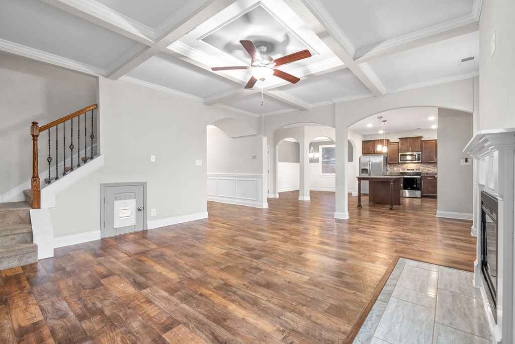 an empty living room with a ceiling fan and a kitchen