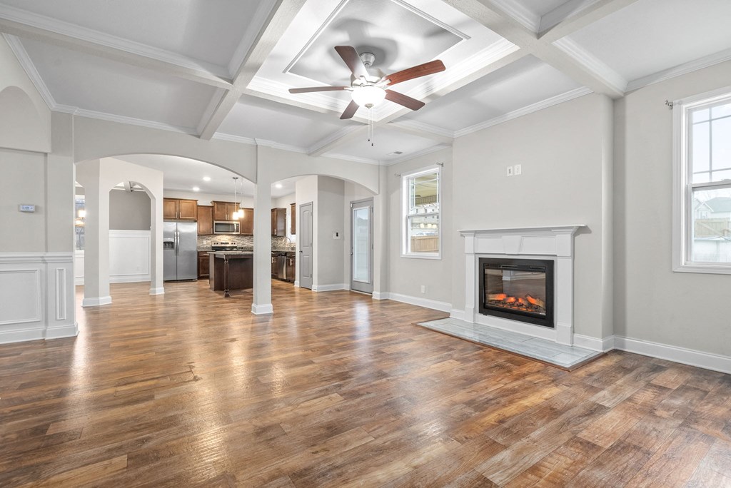 an empty living room with a fireplace and a ceiling fan