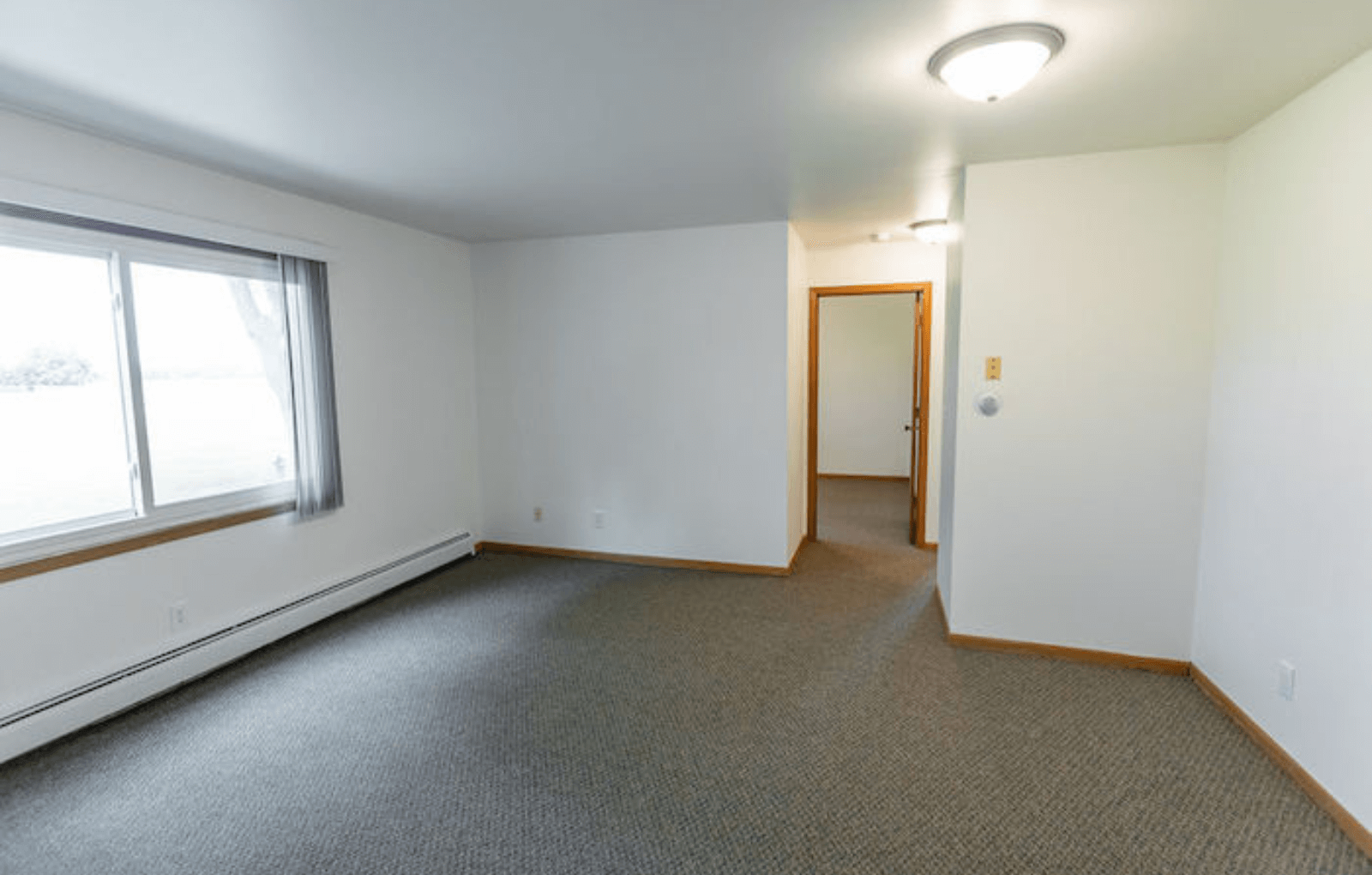 an empty living room with a large window and carpet