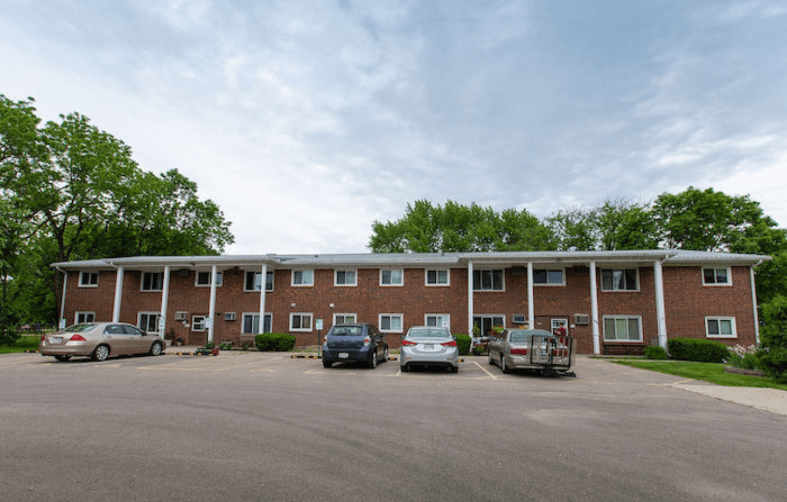 an apartment building with cars parked in a parking lot