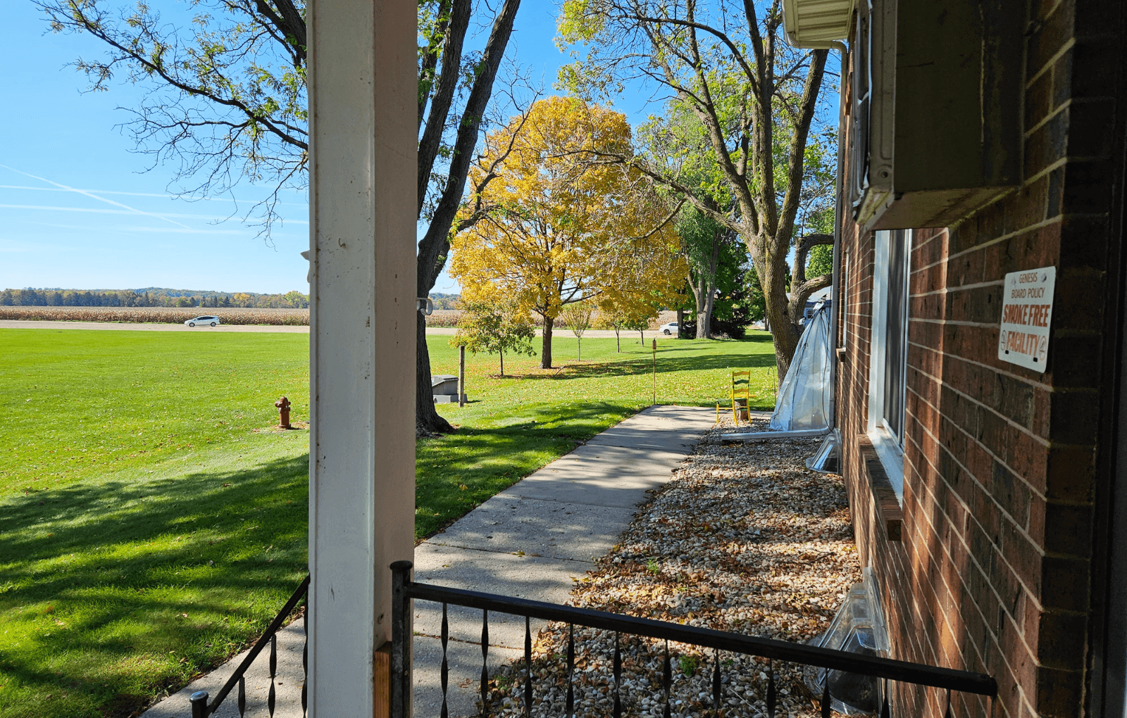 a view of the side of a brick building with a sidewalk and a grass field