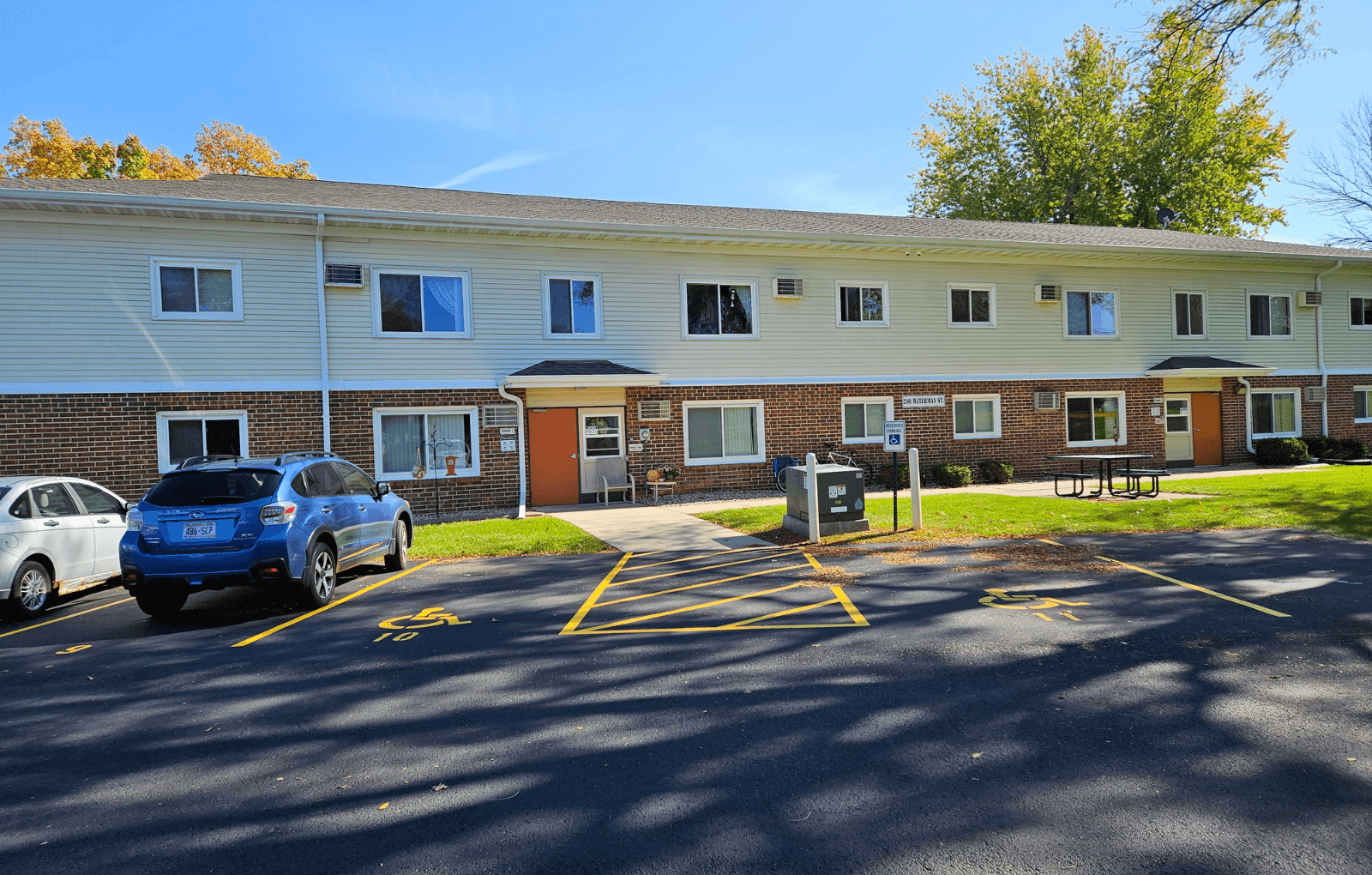 a large brick building with a parking lot and a blue car