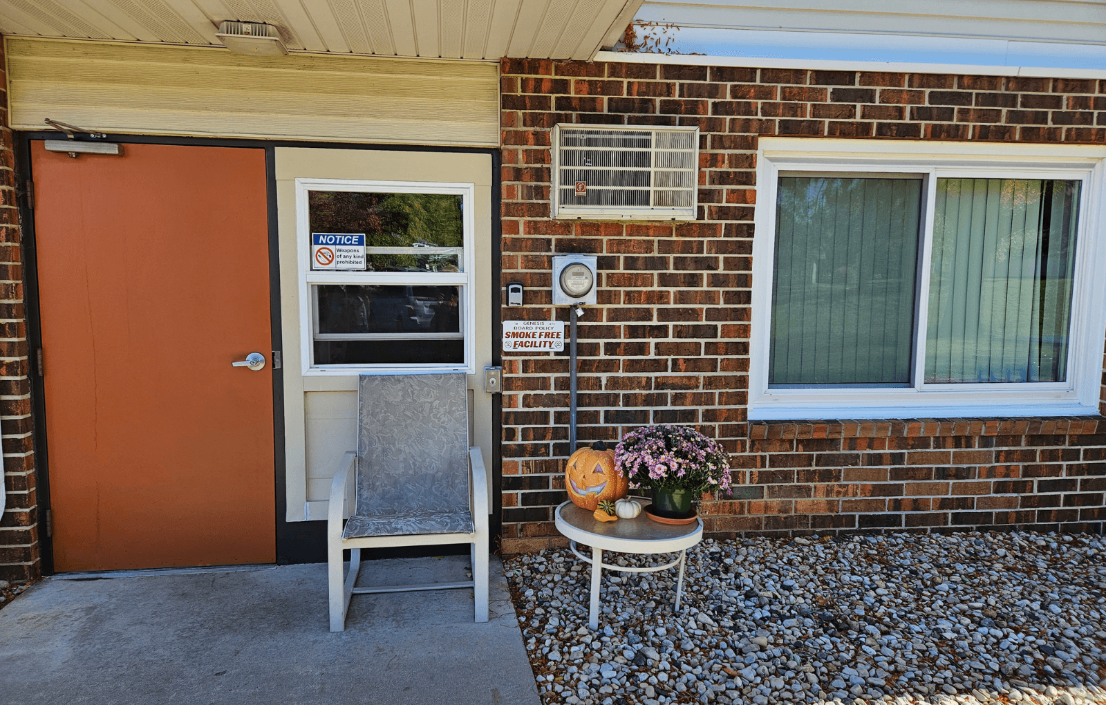 the front door of a brick house with a halloween decoration on a table