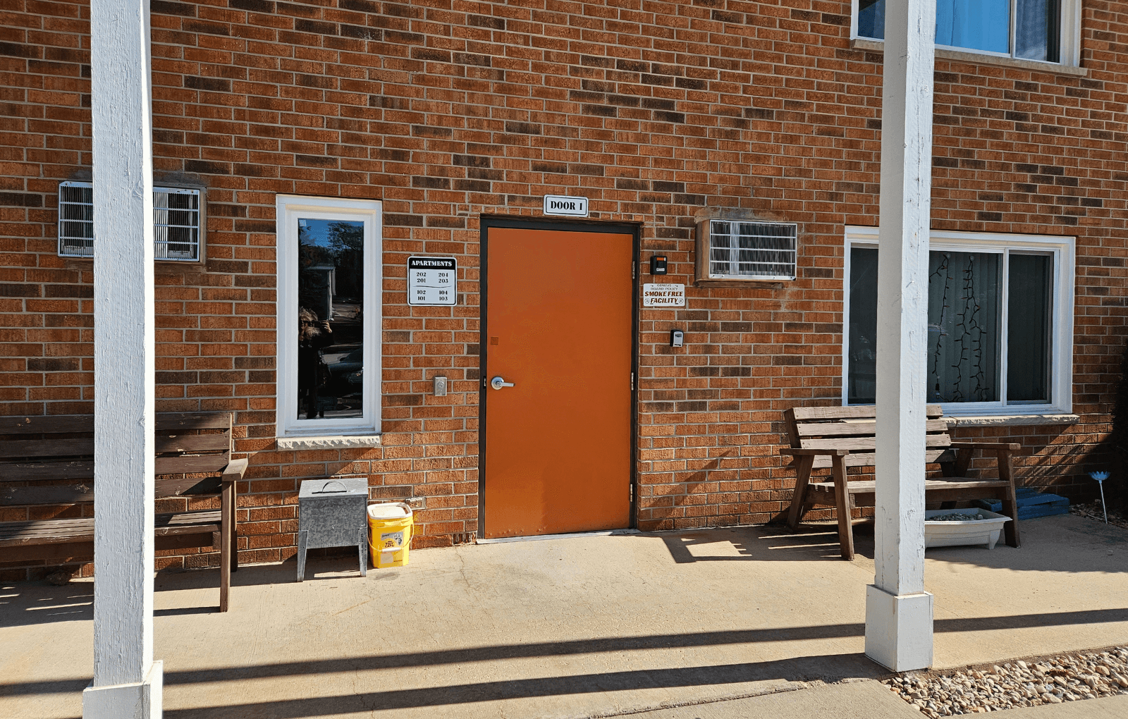 a brick building with a orange door and two wooden benches