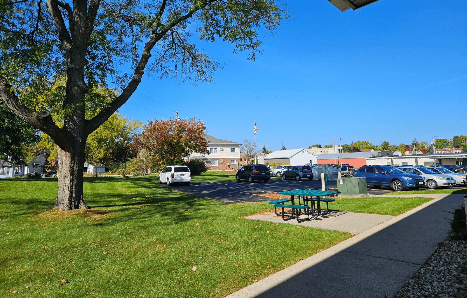 a park with a picnic table and cars parked in a parking lot