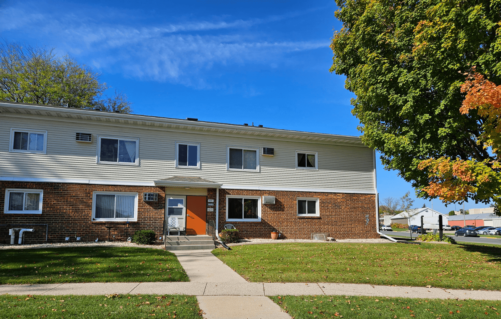 a white house with a orange door and a tree