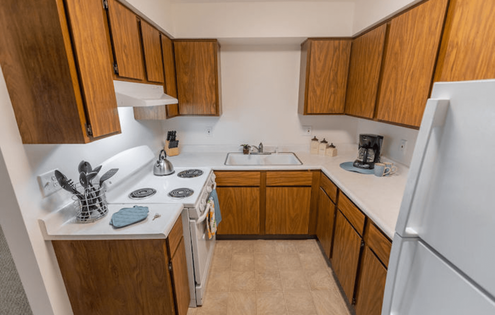 a kitchen with wooden cabinets and white appliances and a refrigerator